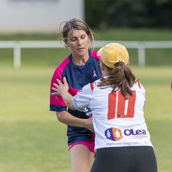 Two players in pink ribbon rugby jerseys during a non-contact touch session