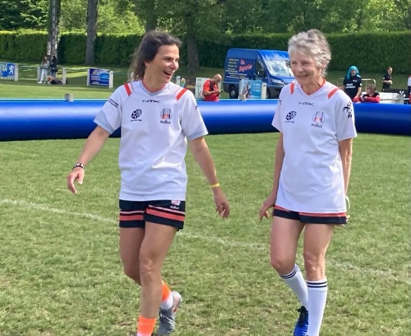 Two women players smiling on the pitch in official Les RUBieS jerseys